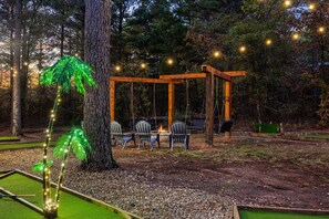 Cozy firepit with string lights and a rustic swing nearby.