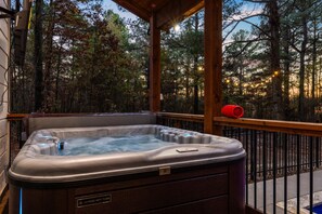 Hot tub on a deck with scenic views and soft lighting.