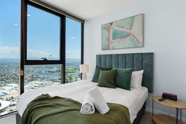Serene master bedroom with a comfortable queen bed, complemented by natural greenery and breathtaking views of the Gold Coast river and hinterland.