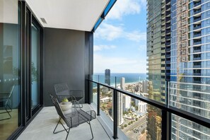 Balcony with ocean views, though slightly obstructed by a nearby building, providing a relaxing spot to enjoy the coastal atmosphere.