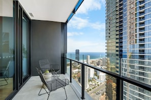 Balcony with ocean views, though slightly obstructed by a nearby building, providing a relaxing spot to enjoy the coastal atmosphere.