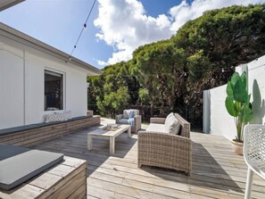 A sun-soaked deck with a BBQ, lounge seating, and festoon lighting, ideal for relaxing evenings.
