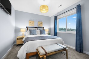 Cozy guest room with blackout curtains, smart TV, and closet space