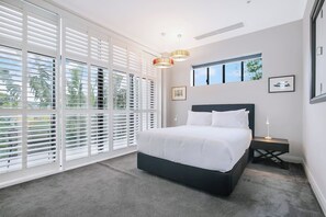 The thoughtfully appointed third bedroom includes a queen-size bed with side tables and reading lamps. 