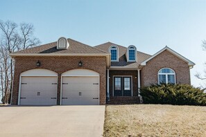 A brick home with two garages and a driveway.