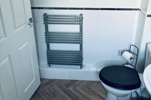 Toilet, sink, vanity, Bath with shower.