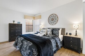 A spacious master bedroom featuring a king-size adjustable bed, a designated workspace, and a private ensuite bath for ultimate comfort.