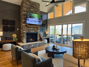 Relax by the cozy stone fireplace and soak in the stunning mountain views from this inviting living room.