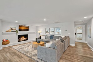 Living room with large sectional, fire place, TV & deck access.