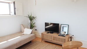 Relax in the lounge area with a smart TV, soft chaise lounge, and a touch of greenery to complement the light, airy vibe.
#ChicLiving #PortoVibes #LovelyStay