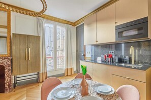 Salon avec canapé, table basse, TV, table à manger et chaises, cuisine ouverte