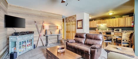 Inviting living room featuring comfortable seating, a flat-screen TV, a ceiling fan, and a cozy fireplace.