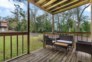 Relax on the cozy back porch with seating and serene wooded views.