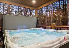 The hot tub beckons with its warm, bubbling waters and forest views, creating a private oasis for ultimate relaxation.