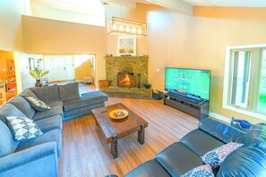 Family room with 75 inch TV and wood burning fire place.