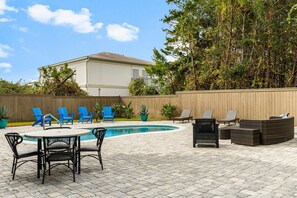 The backyard features a stunning inground pool, beautifully framed by ample outdoor dining, seating, and lounging creating a perfect space for relaxation and entertainment.