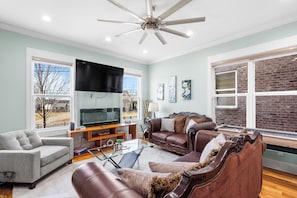 Cozy living area with an electric fire place, sofas, coffee table and a fan.