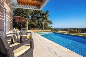 Seating area at the pool with view to the valley and distance sea view.