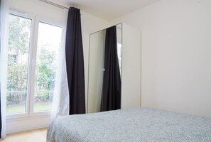 Chambre avec lit de 160 et armoire avec accès porte fenêtre qui donne sur le jardin.