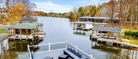 Spacious outdoor deck with comfortable seating, lounge chairs, and scenic views of a wooded area and water.