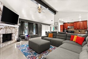 Relax in this spacious living room featuring vaulted ceilings, a cozy fireplace, and a large sectional perfect for gathering with family and friends.