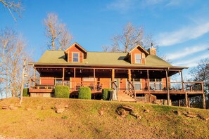 Charming log cabin with a spacious front porch, perfect for relaxing and soaking in the countryside atmosphere.