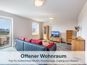 heller, offener Wohnraum mit Flat-TV und Balkonzugang