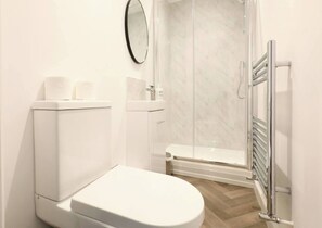 Stylish bathroom with a modern shower, sleek fixtures, and complimentary toiletries, designed for comfort and convenience.