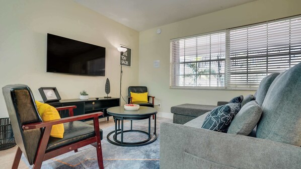 Cozy living room with modern decor, perfect for relaxing with a movie or enjoying natural light through large windows.