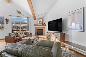 Living area featuring a large smart TV, gas fireplace, and balcony access.