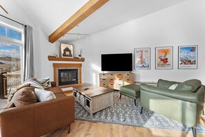 Living area featuring a large smart TV, gas fireplace, and balcony access.