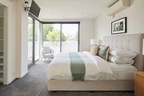 Retreat to the primary bedroom, offering luxurious bedding, tasteful decor, a wall-hung TV and access to a balcony for your morning coffee.