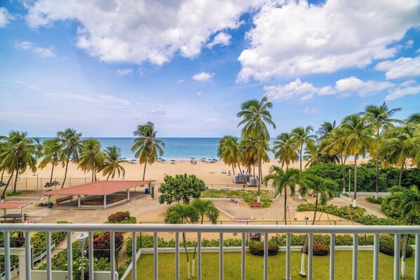 Balcony View – Wake up to swaying palms, golden sands, and endless ocean blues from your private beachfront balcony in Isla Verde.