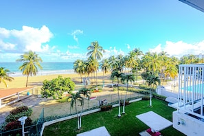 Balcony View – Soak in vibrant coastal vibes and lush palm-lined scenery just steps away from Isla Verde Beach.