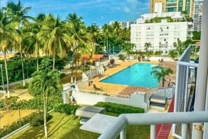 Balcony View – Enjoy a lush tropical escape with poolside vibes and towering palms just minutes from the beach.