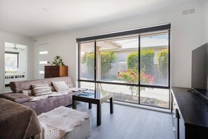 Bright living area with large windows overlooking the garden, offering a peaceful retreat.
