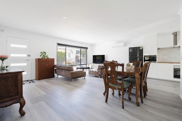 Spacious dining area adjacent to a fully equipped kitchen, perfect for shared meals and entertaining.

