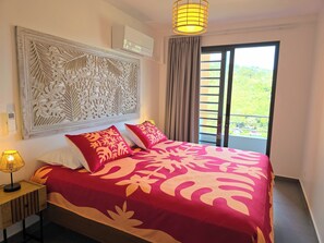 Chambre principale avec décoration polynésienne et vue sur la vallée.