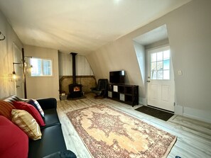 Living room with a futon and wood burning fireplace.