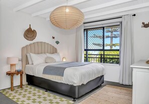 The thoughtfully furnished first bedroom includes a queen-size bed with side tables and reading lamps.