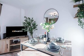 The living room features a comfortable sofa bed, a smart TV, and an open-plan dining area, perfect for relaxing and entertaining. Large doors offer easy access to the backyard, creating a seamless connection between indoor and outdoor living spaces.