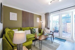 The living room features a comfortable sofa bed, a smart TV, and an open-plan dining area, perfect for relaxing and entertaining. Large doors offer easy access to the backyard, creating a seamless connection between indoor and outdoor living spaces.