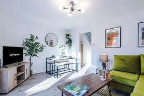 The living room features a comfortable sofa bed, a smart TV, and an open-plan dining area, perfect for relaxing and entertaining. Large doors offer easy access to the backyard, creating a seamless connection between indoor and outdoor living spaces.