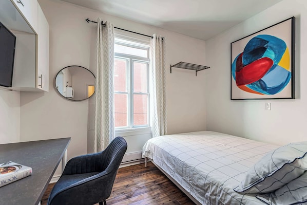 Cozy queen-sized bed with soft linens, natural light, and stylish artwork.