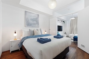 Discover a stylish bedroom that boasts a queen-sized bed adorned with elegant blue bedding and a convenient bedside table for your essentials.