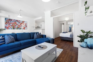 Open-plan living room featuring a comfortable couch, a chic coffee table, and a view of the adjoining bedroom, creating a seamless flow between spaces.