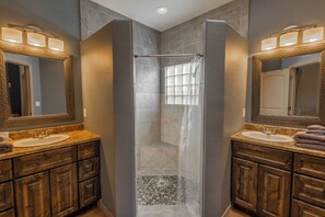 Bathroom 1 with two sinks, walk-in shower with two showerheads and bench.