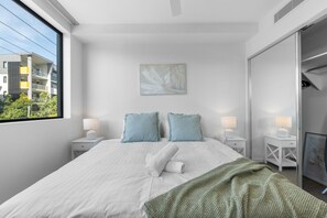 Matching bedside tables with lamps add style and functionality to the cozy bedroom space.