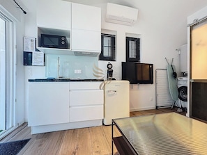 Cette pièce accueille une cuisine moderne et minimaliste. La table basse au design épuré invite à la détente. L'espace optimise chaque centimètre avec son lave-linge intégré et son climatiseur assurant confort en toute saison.
