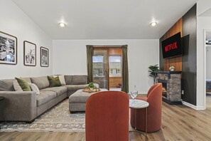 Main level living room with large sectional coach, electric fireplace, 50" smart TV, and walkout access to the 4 season porch.